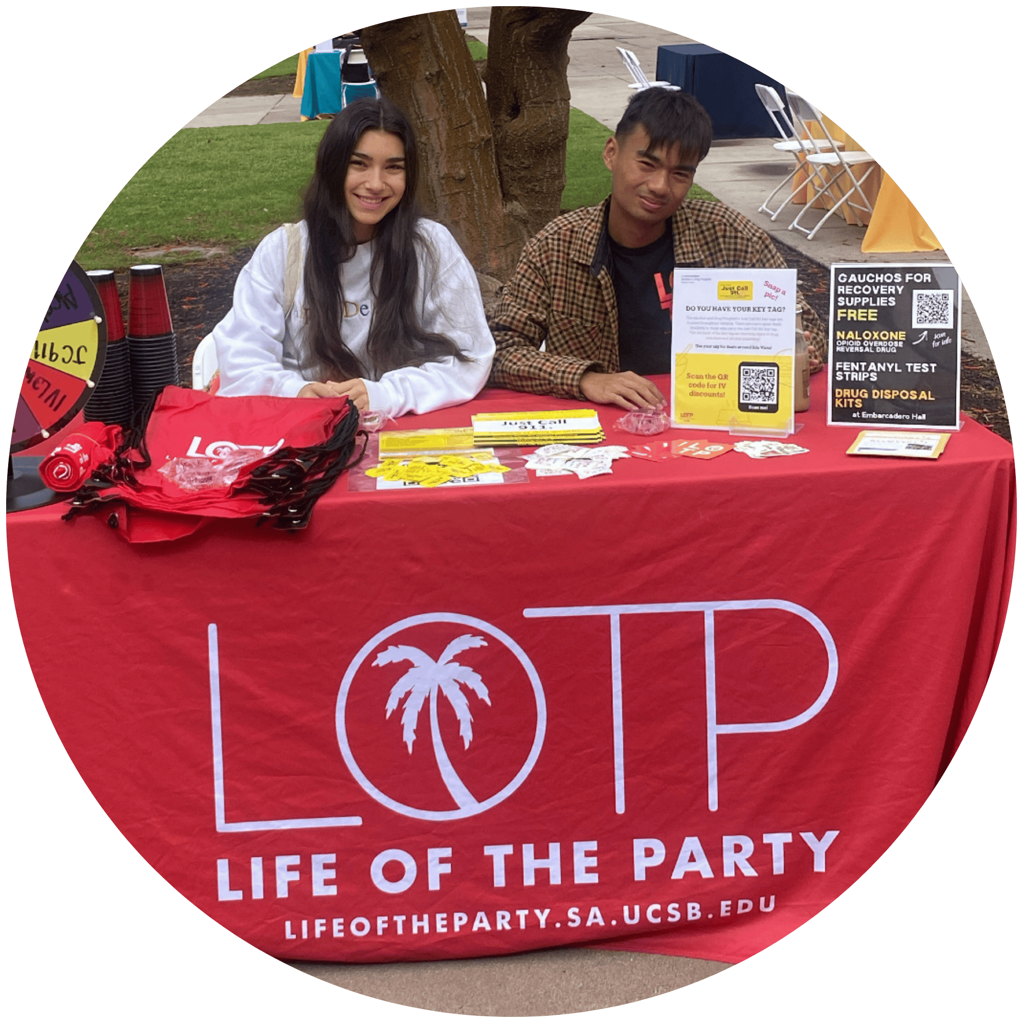 This image depicts two members of the Life of the Party (LOTP) team, sitting at a red table with the LOTP logo.